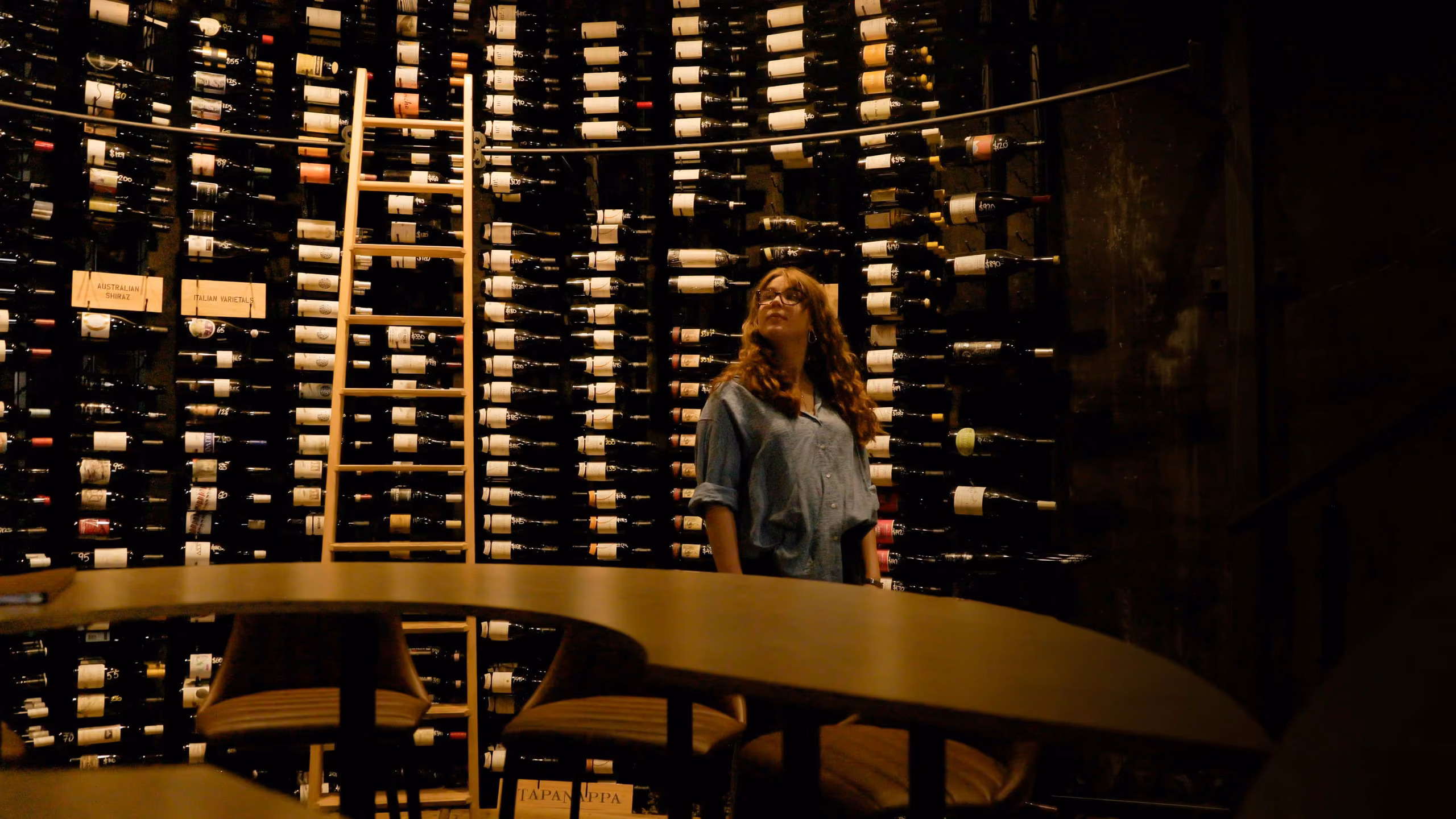 Guest browsing the floor-to-ceiling wine racks in The Tank
