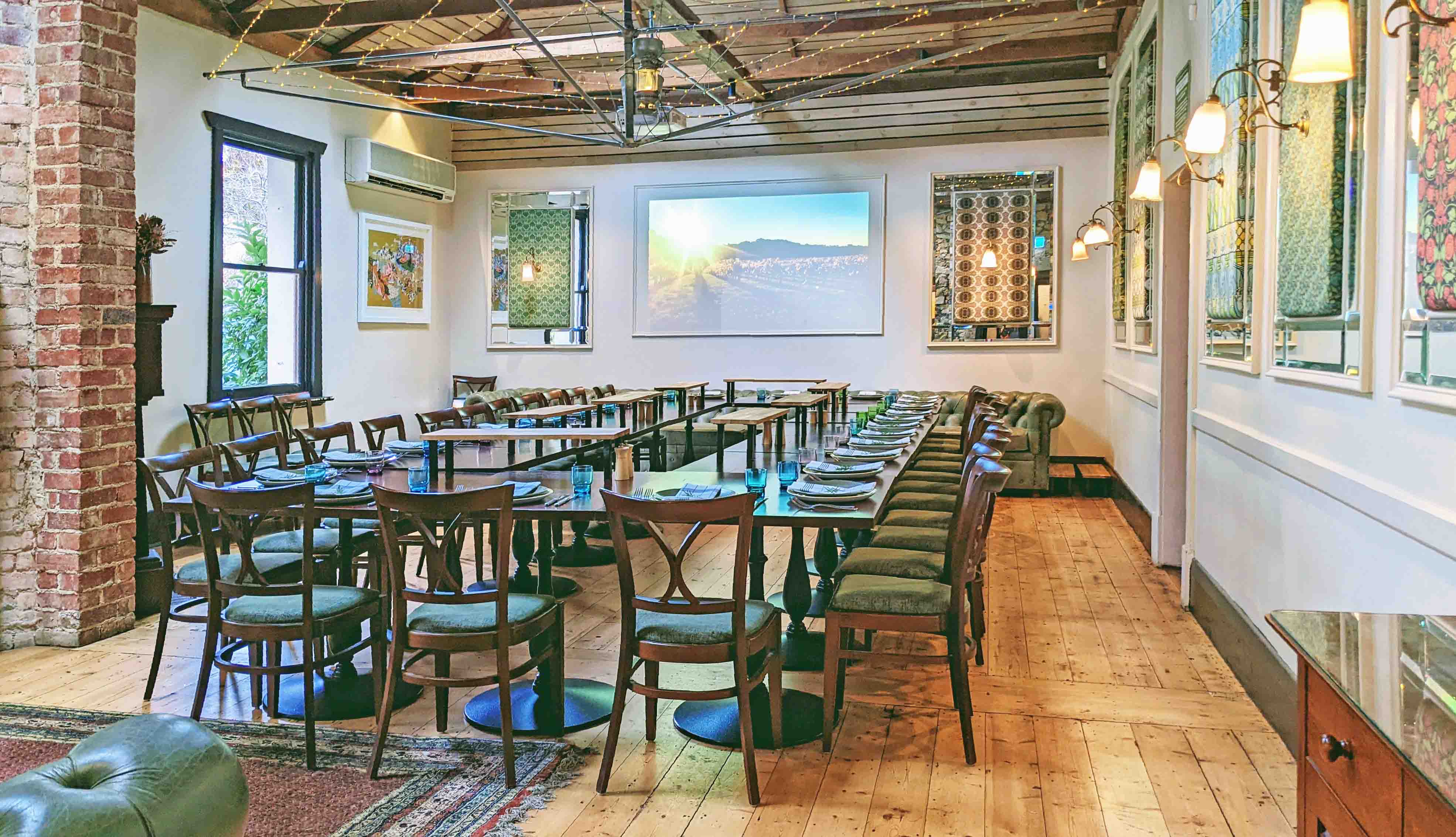 Hills Hoist function room set with long tables and a projector screen