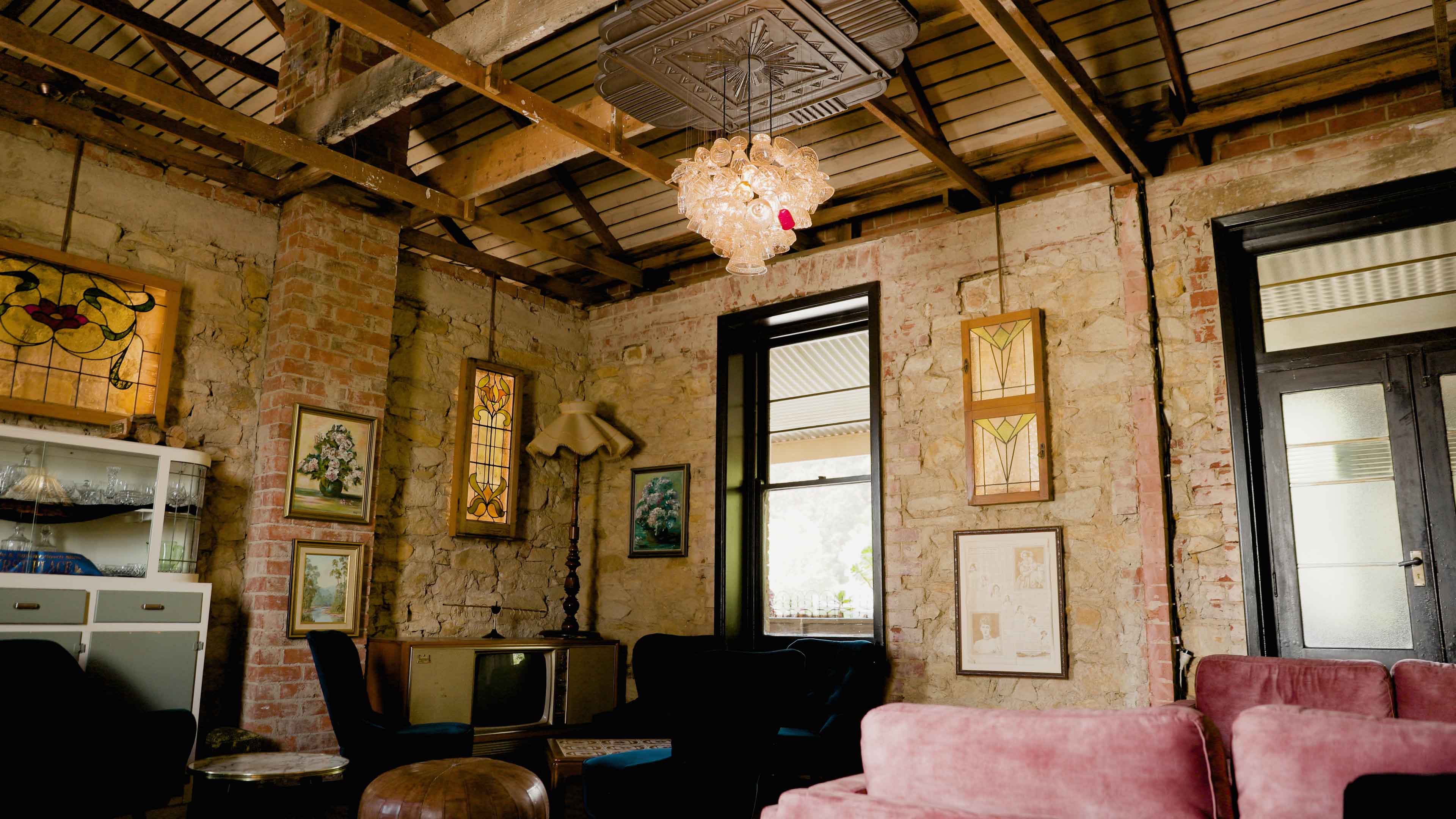 Lounge with exposed brick walls, artwork and a pink sofa