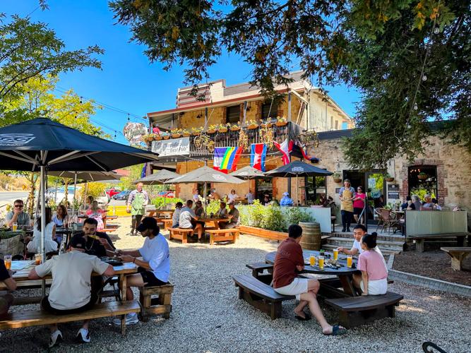 Busy beer garden in the sun with umbrellas in front of the Uraidla Hotel